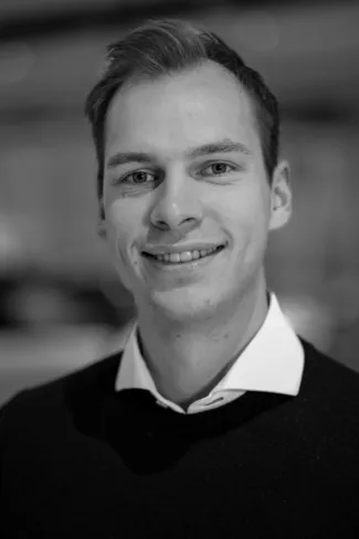 Smilende mann i svart genser og hvit skjorte