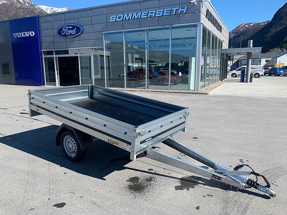Biltilhenger parkert foran bilforhandler i solskinn