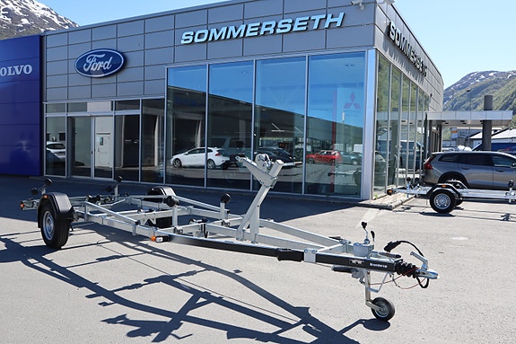 Tilhenger foran bilforhandler i solfylt vær.